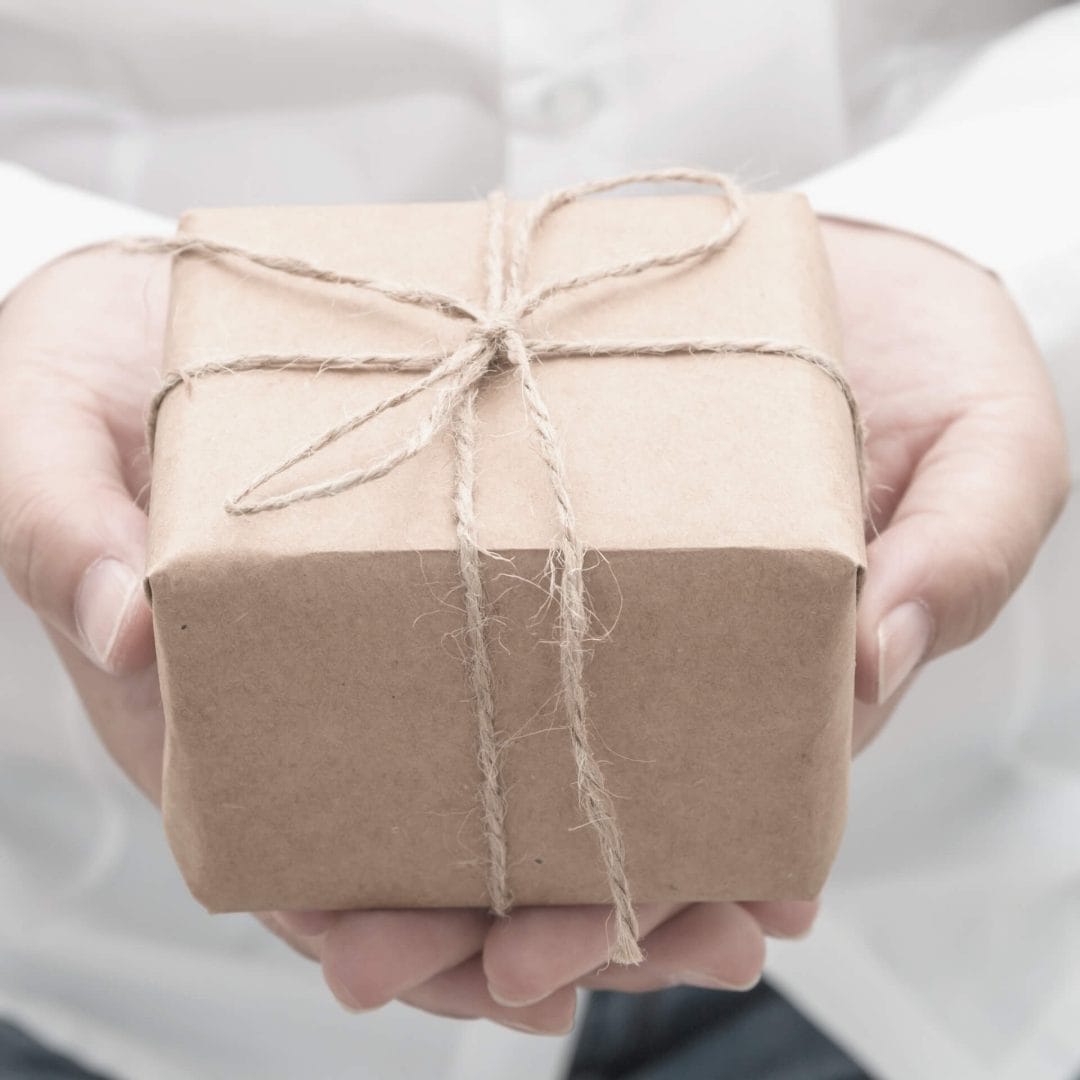 Donor Retention: Person holding a gift box as if to give the viewer a present.