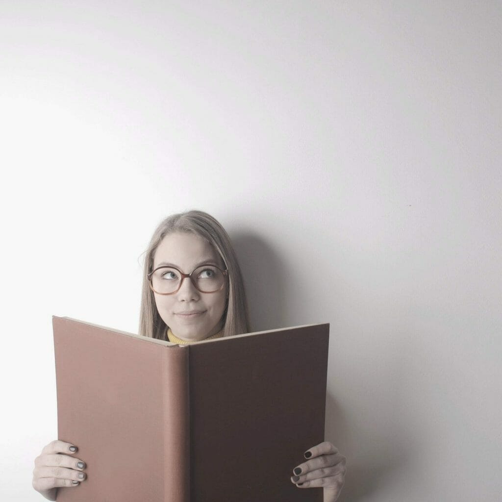 Woman thinking about nonprofit storytelling while holding big book